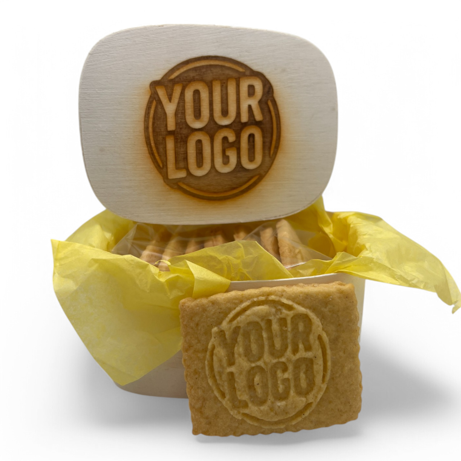 Holzkästchen mit gelasertem Logo im Deckel, gefüllt mit 8 Logokeksen in gelbem Seidenpapier – ein Keks zur Ansicht vorn platziert